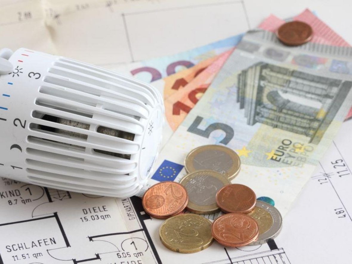 Geld liegt neben einem Heizungsregler